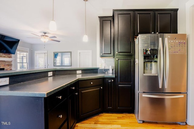 kitchen featuring stainless steel fridge with ice dispenser, a ceiling fan, dark countertops, a peninsula, and light wood-style flooring