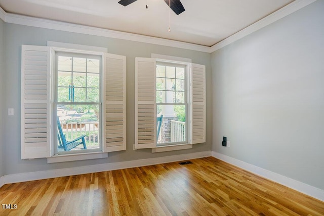 empty room featuring ornamental molding, healthy amount of natural light, baseboards, and wood finished floors