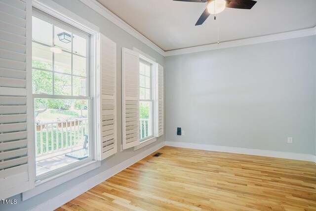 empty room with crown molding, light wood-type flooring, plenty of natural light, a ceiling fan, and baseboards