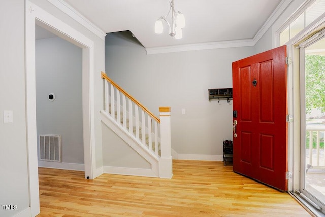foyer entrance featuring crown molding, light wood-type flooring, stairs, baseboards, and a chandelier