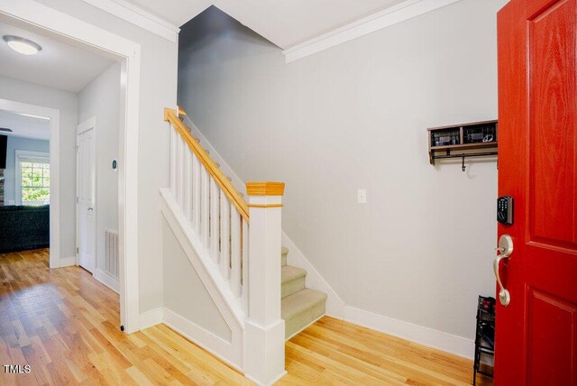 staircase featuring wood finished floors, baseboards, and crown molding