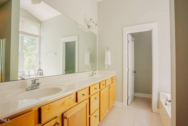 full bathroom featuring tile patterned floors, double vanity, a tub, and baseboards