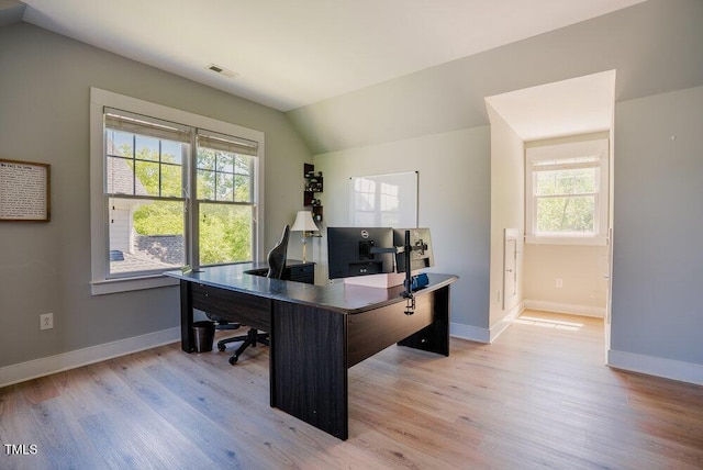office space with light wood-style floors, vaulted ceiling, healthy amount of natural light, and baseboards