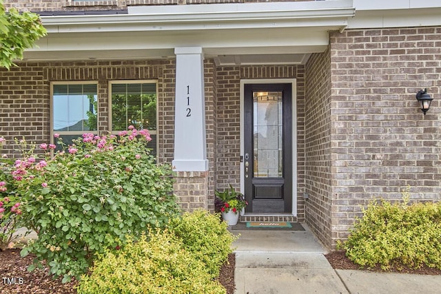 doorway to property featuring brick siding and a porch