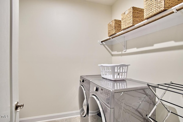 clothes washing area with washer and clothes dryer and baseboards