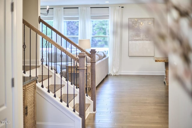 staircase with healthy amount of natural light, hardwood / wood-style flooring, and baseboards