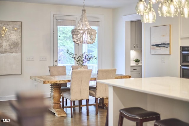 dining area featuring a chandelier, wood finished floors, and baseboards