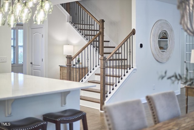 stairway featuring wood finished floors, a chandelier, and baseboards