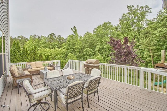 wooden deck with an outdoor hangout area, area for grilling, and a wooded view