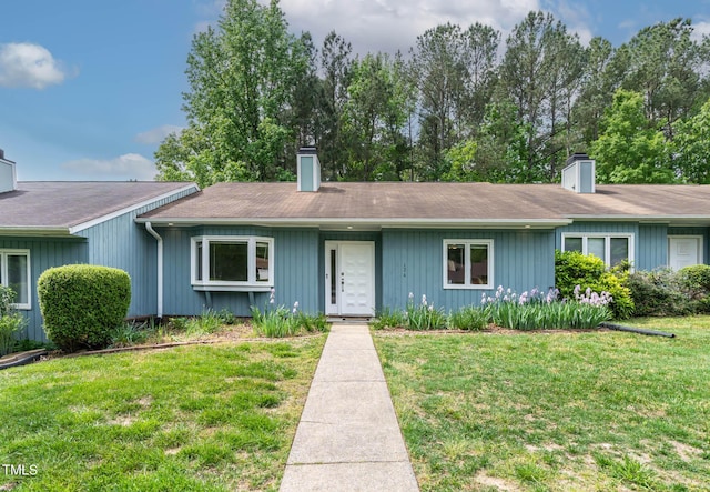ranch-style house with a chimney and a front yard