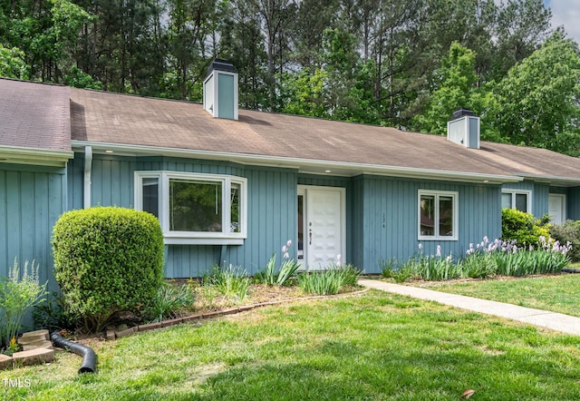 single story home featuring a chimney and a front lawn