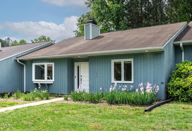 view of front of home with a chimney, a front lawn, and roof with shingles