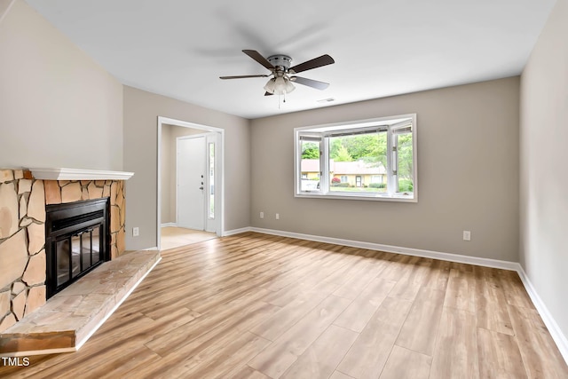 unfurnished living room featuring ceiling fan, light wood-type flooring, a fireplace, and baseboards