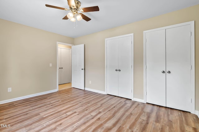unfurnished bedroom with two closets, light wood-style floors, baseboards, and a ceiling fan