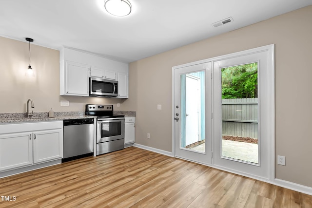 kitchen featuring stainless steel appliances, a sink, light wood-type flooring, white cabinetry, and light stone countertops