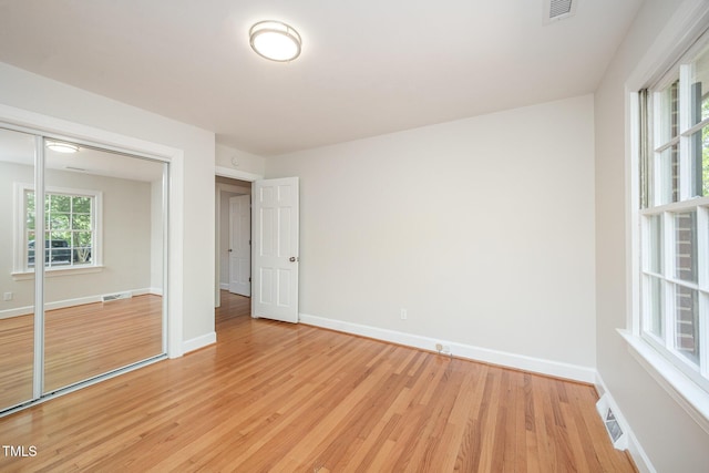 unfurnished bedroom with light wood-style floors, baseboards, and a closet