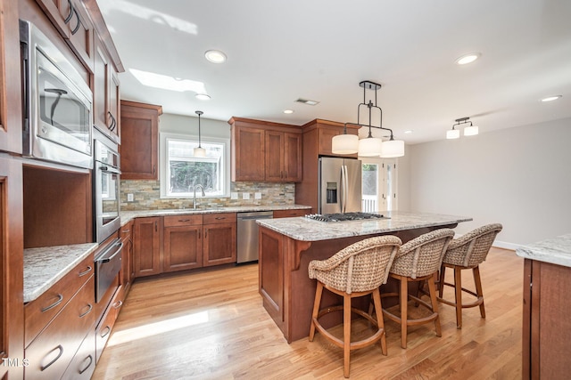 kitchen with stainless steel appliances, a warming drawer, decorative backsplash, a kitchen island, and a breakfast bar