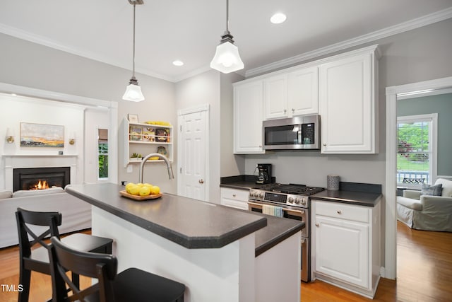 kitchen featuring appliances with stainless steel finishes, dark countertops, open floor plan, light wood-style floors, and crown molding