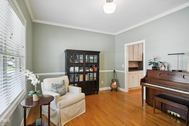 sitting room with plenty of natural light, light wood-type flooring, crown molding, and baseboards