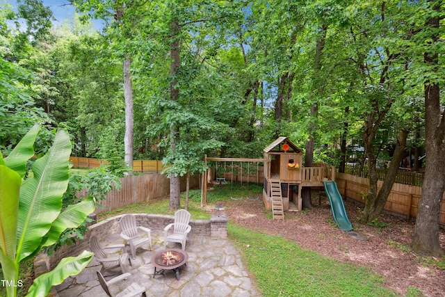fenced backyard with a playground, an outdoor fire pit, and a patio area