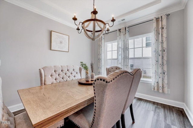 dining room with ornamental molding, a chandelier, dark wood finished floors, baseboards, and a tray ceiling