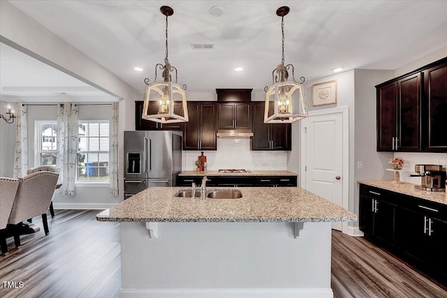 kitchen with appliances with stainless steel finishes, a chandelier, dark wood-type flooring, a kitchen breakfast bar, and a sink