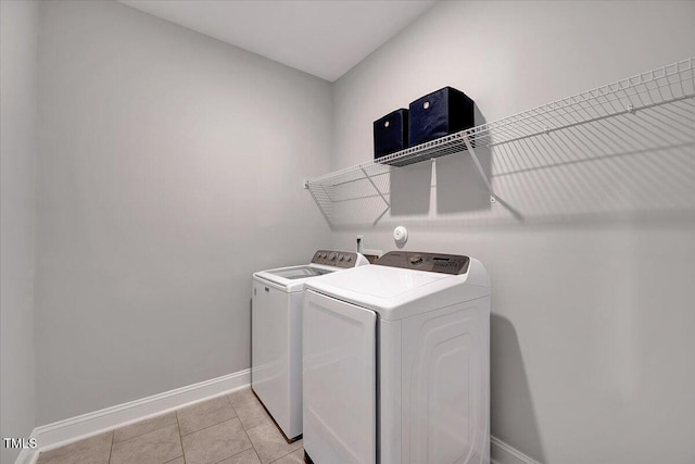 laundry area with washing machine and clothes dryer, baseboards, and light tile patterned flooring