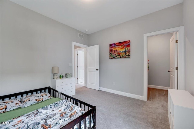 bedroom with light colored carpet, baseboards, and a nursery area