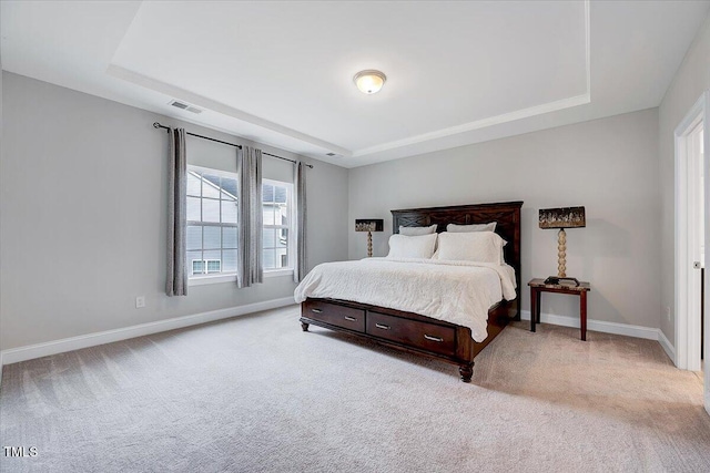 bedroom featuring a raised ceiling and light carpet