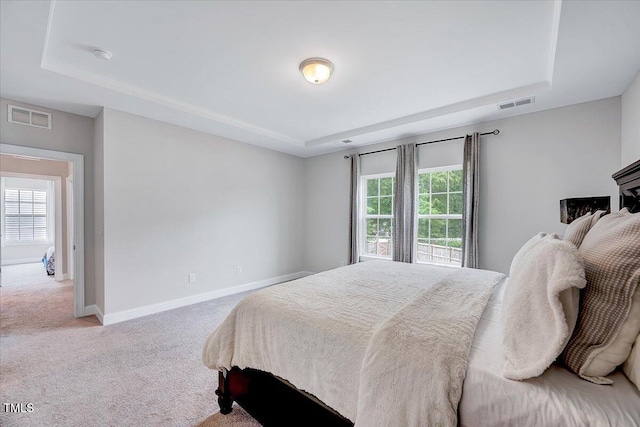 carpeted bedroom with a tray ceiling and baseboards