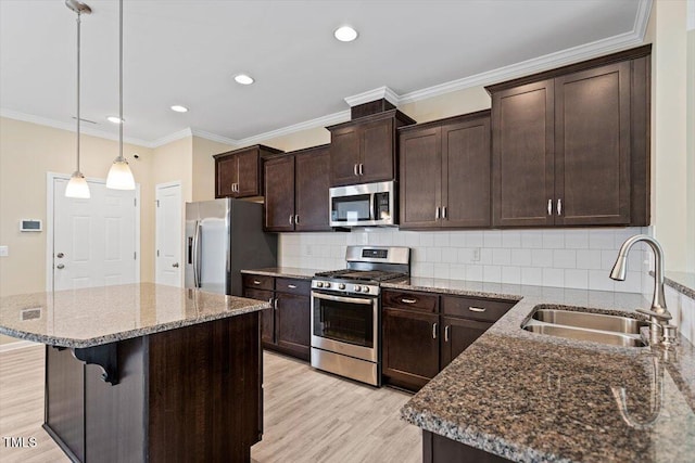 1027 Myers Point Dr, Morrisville, NC 27560 - kitchen featuring stainless steel appliances, a sink, light wood-style flooring, dark brown cabinets, and dark stone countertops