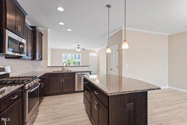 1027 Myers Point Dr, Morrisville, NC 27560 - kitchen with stainless steel appliances, a sink, crown molding, light wood-type flooring, and backsplash