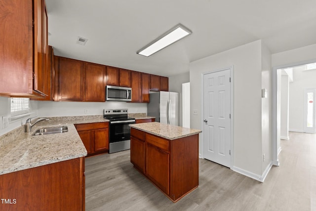 204 Trevor Ridge Dr, Holly Springs, NC 27540 - kitchen featuring appliances with stainless steel finishes, light wood-style flooring, a center island, and light stone countertops