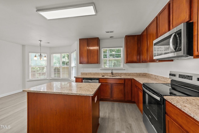 204 Trevor Ridge Dr, Holly Springs, NC 27540 - kitchen with appliances with stainless steel finishes, light wood-style floors, a center island, a chandelier, and light stone counters