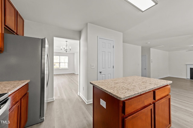 204 Trevor Ridge Dr, Holly Springs, NC 27540 - kitchen featuring light wood finished floors, freestanding refrigerator, a chandelier, and a kitchen island