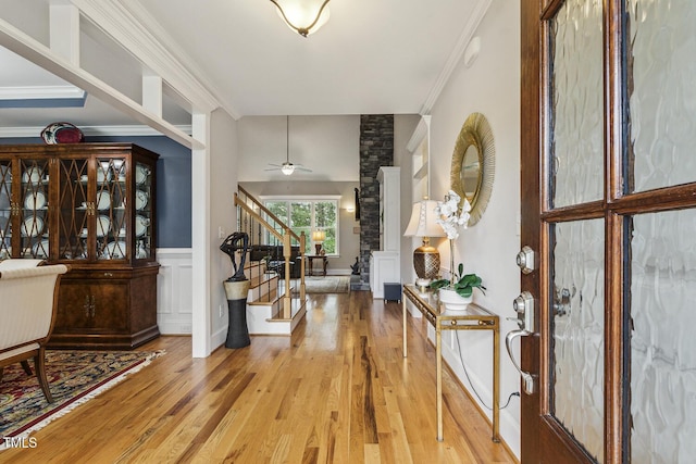 entryway featuring stairway, light wood-style flooring, crown molding, and ceiling fan