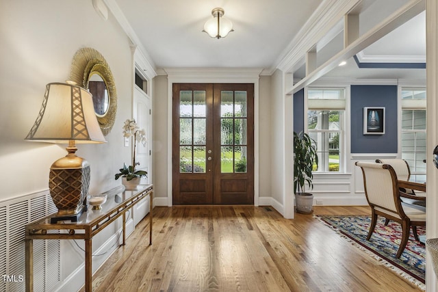 foyer entrance featuring healthy amount of natural light, crown molding, wood finished floors, and baseboards