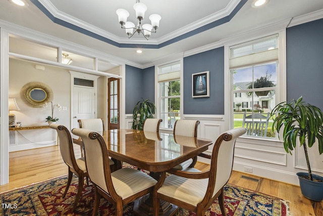 dining room with a chandelier, wood finished floors, crown molding, wainscoting, and recessed lighting