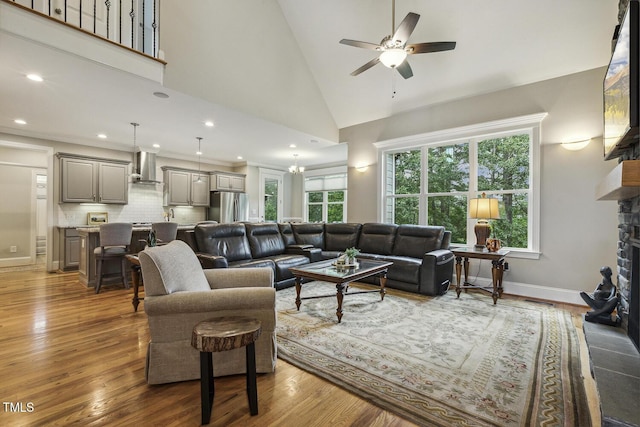 living area featuring a ceiling fan, a fireplace, wood finished floors, recessed lighting, and baseboards
