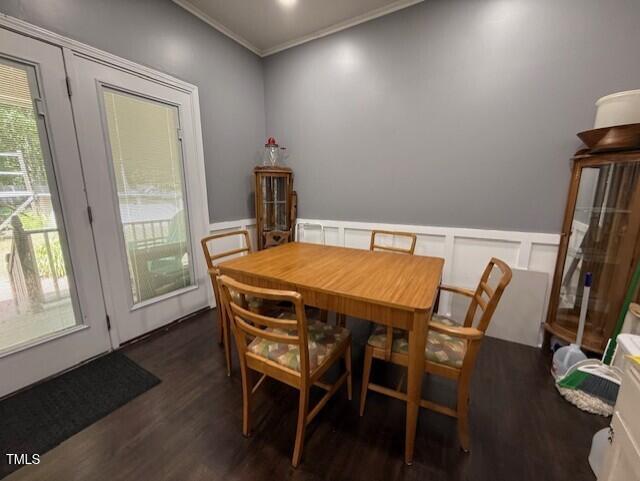 dining area featuring a decorative wall, wood finished floors, crown molding, healthy amount of natural light, and a wainscoted wall