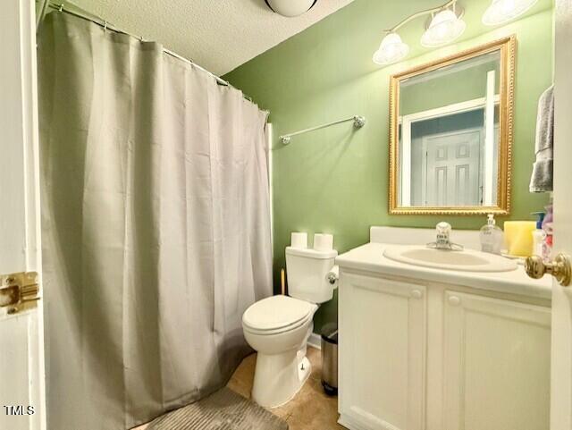 full bathroom featuring toilet, vanity, a textured ceiling, and curtained shower