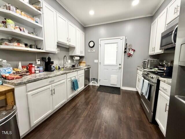 kitchen featuring a sink, stainless steel appliances, ornamental molding, white cabinets, and dark wood-type flooring