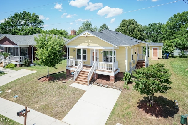 view of front of property with covered porch, stairway, a front lawn, and a shingled roof