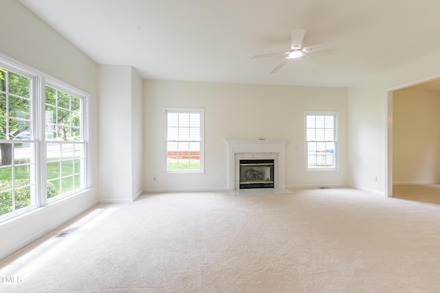 unfurnished living room with healthy amount of natural light, a fireplace, and light colored carpet
