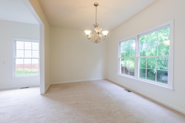 empty room featuring light carpet, a chandelier, and baseboards