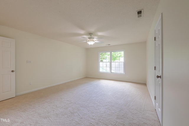 spare room featuring light carpet, ceiling fan, and baseboards