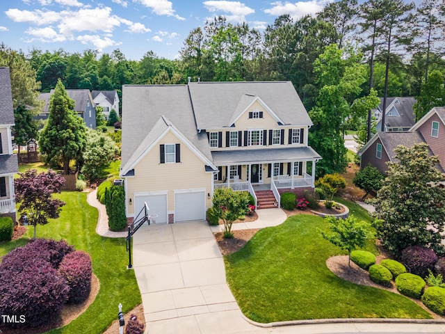 colonial home with covered porch, a garage, concrete driveway, and a front yard