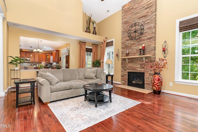 living room with dark wood finished floors, a towering ceiling, a chandelier, and plenty of natural light