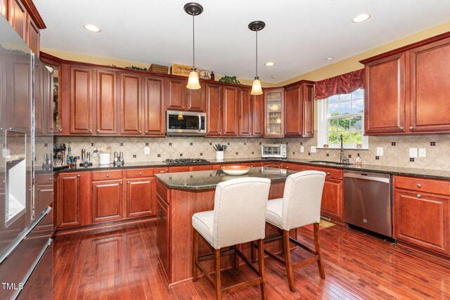 kitchen featuring stainless steel appliances, dark wood finished floors, a breakfast bar, glass insert cabinets, and recessed lighting