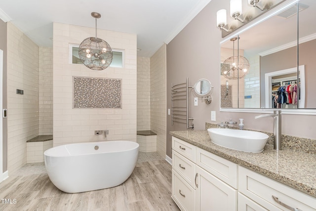 full bathroom with a chandelier, wood finished floors, crown molding, and a freestanding tub
